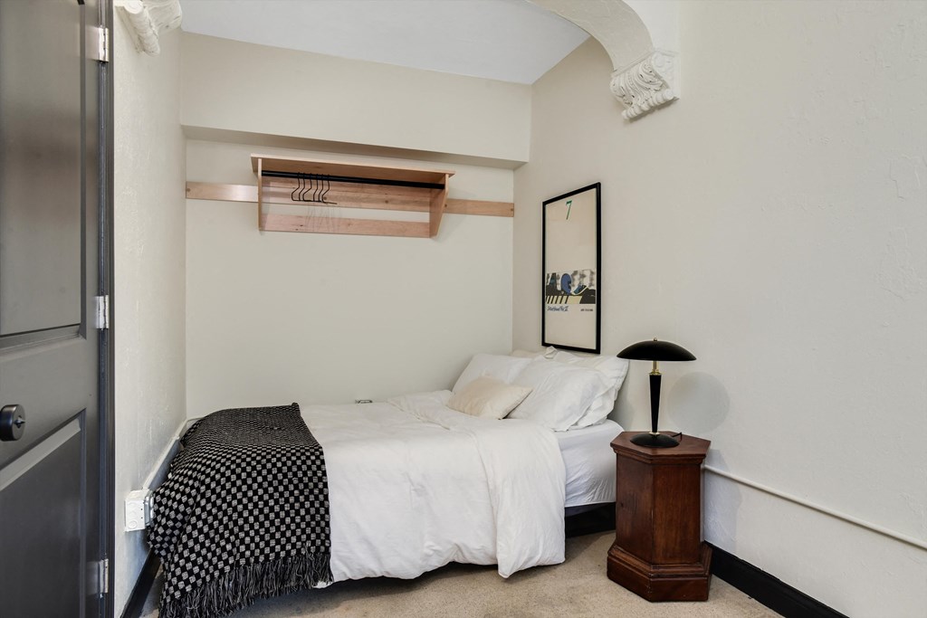 a white bedroom with a bed and a nightstand