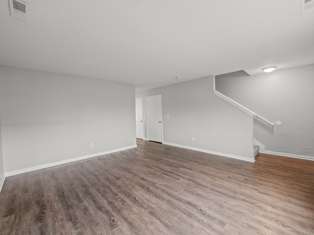 an empty living room with wood flooring and white walls
