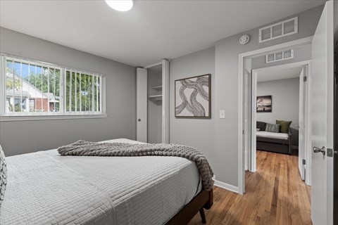 A bedroom with a large bed and a view of the backyard through the window.