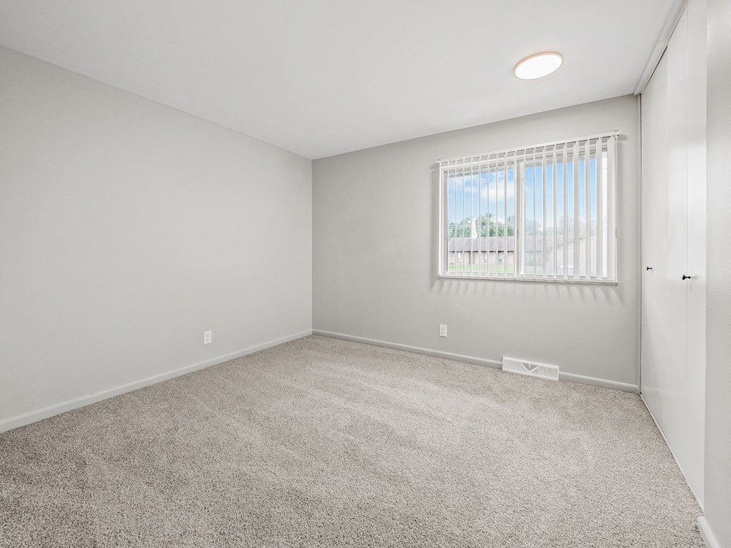 a bedroom with a large window and a carpeted floor