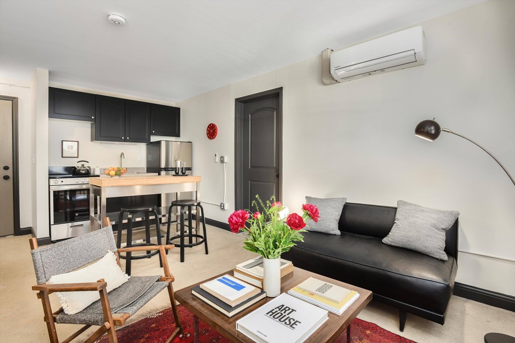 A black couch sits in a living room with a coffee table in front of it.