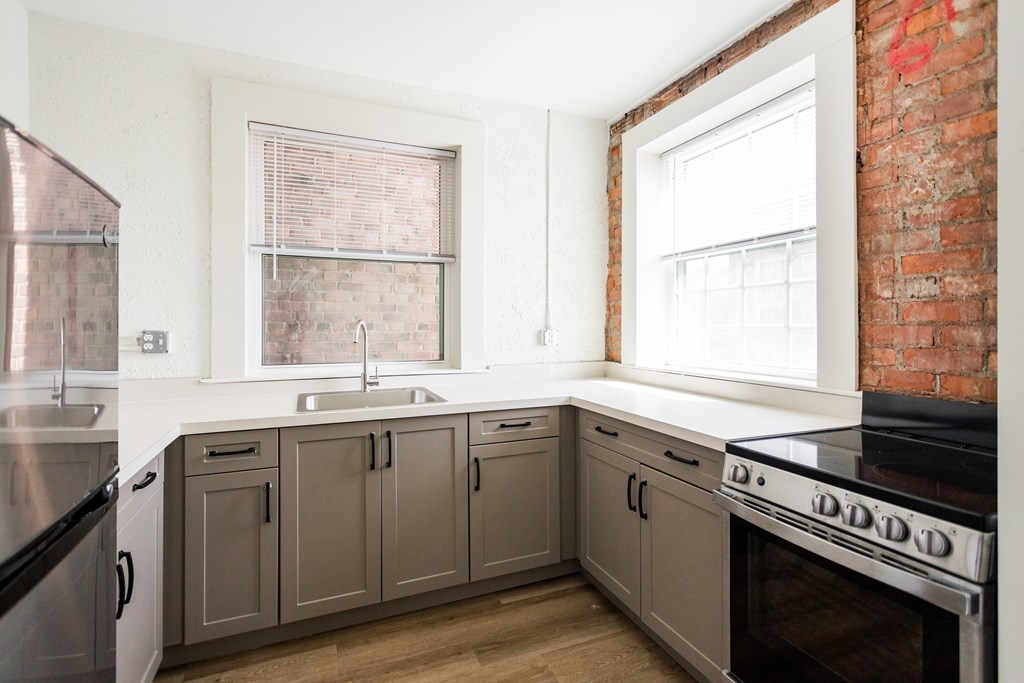 A kitchen with a brick wall and wooden floors.