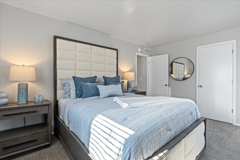 A bedroom with a large bed and a mirror on the wall.