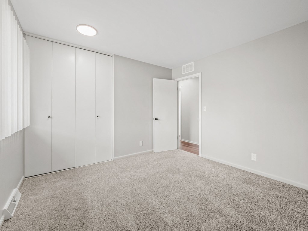 a bedroom with white walls and carpet