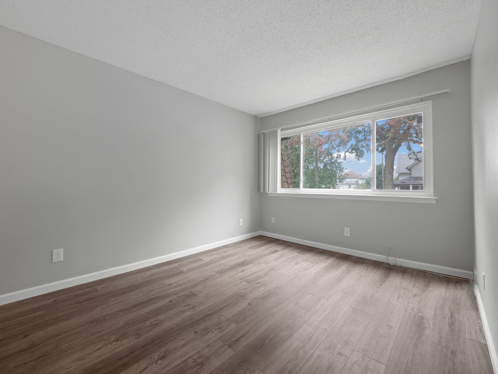 an empty room with wood floors and a window