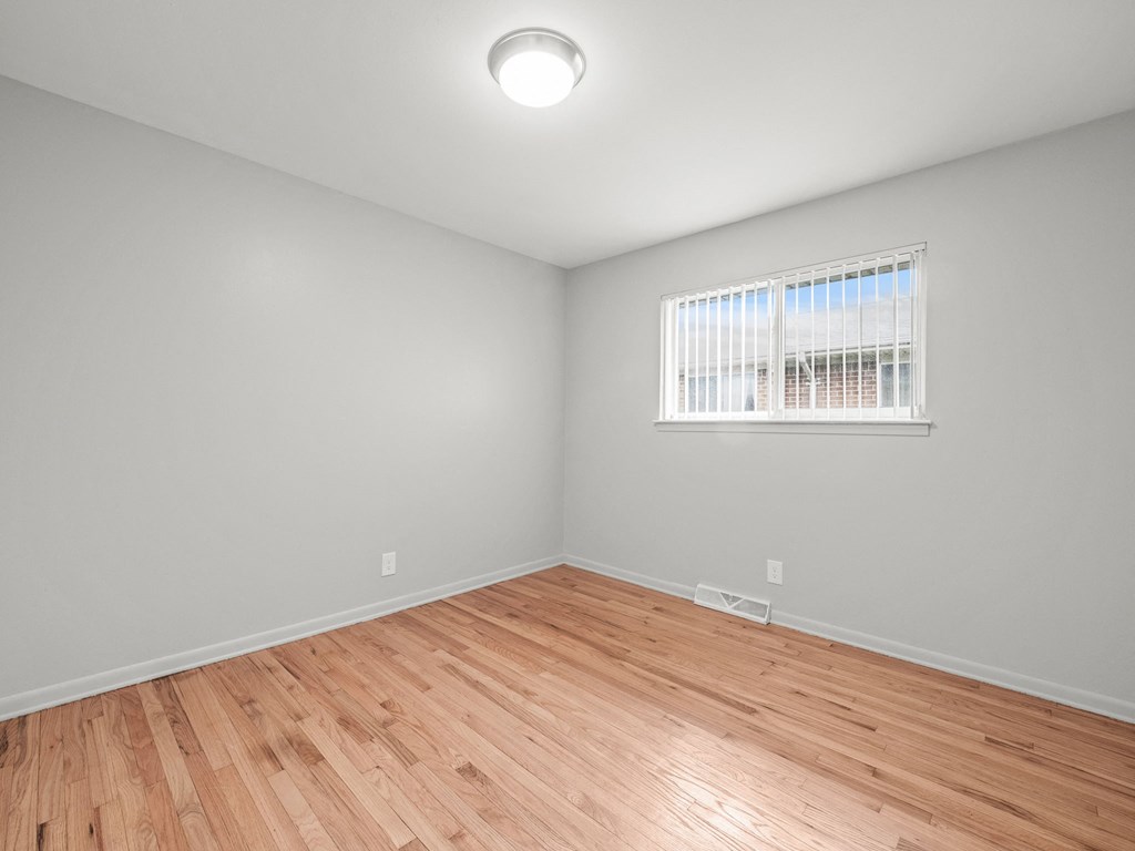 a bedroom with a hardwood floor and a large window