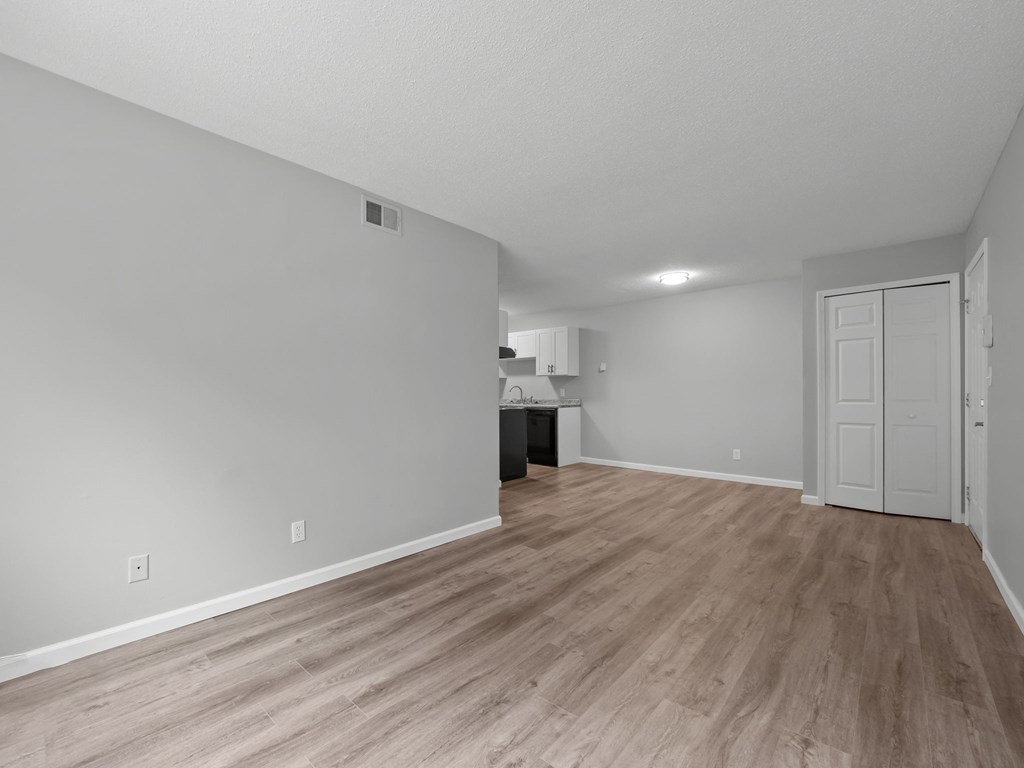 the living room and kitchen of an apartment with wood flooring