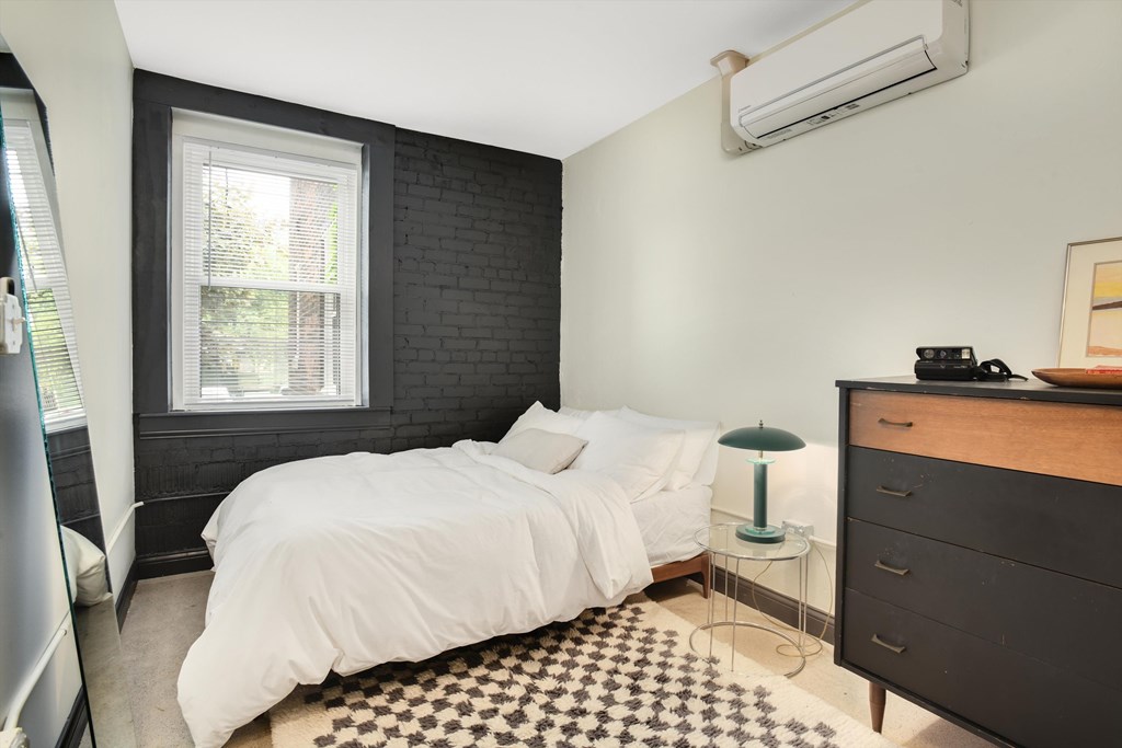 A bedroom with a white bed and a black and white checkered rug.