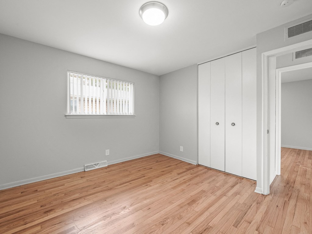 a bedroom with hardwood floors and grey walls