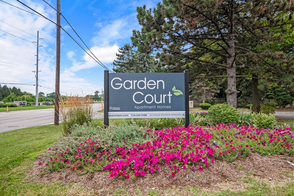 A sign for Garden Court Apartments is surrounded by flowers.