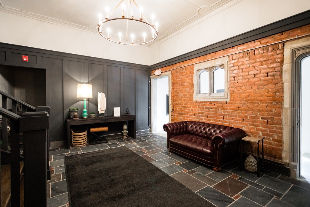 A room with a red brick wall and a brown leather couch.