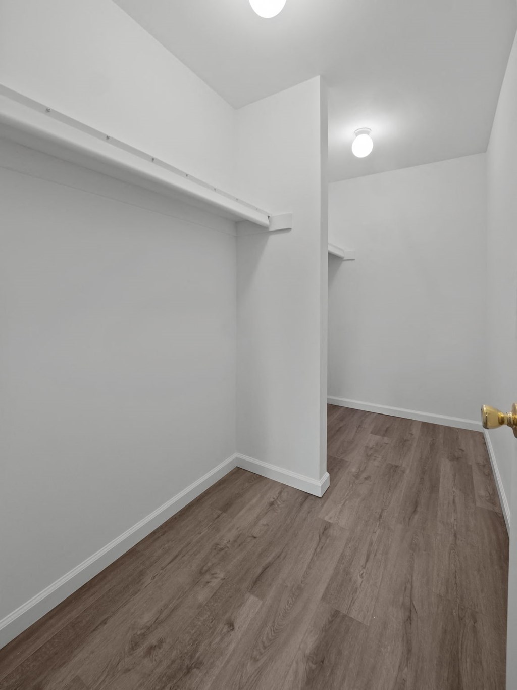 a bedroom with white walls and wood flooring and a closet