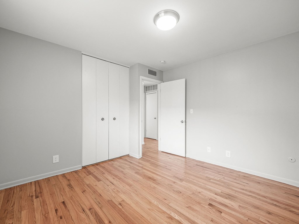 a bedroom with white walls and hardwood floors