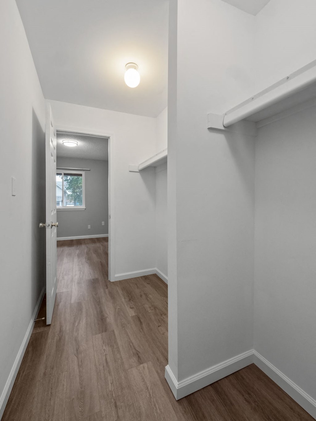a renovated living room and hallway with white walls and wood floors