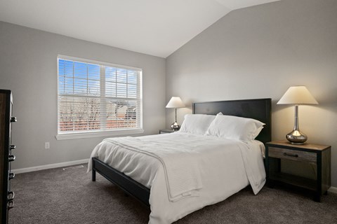 A bedroom with a large bed and two lamps.