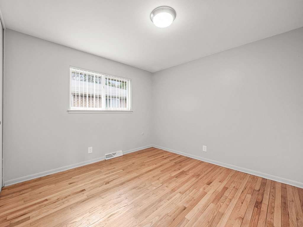 a bedroom with grey walls and a wooden floor