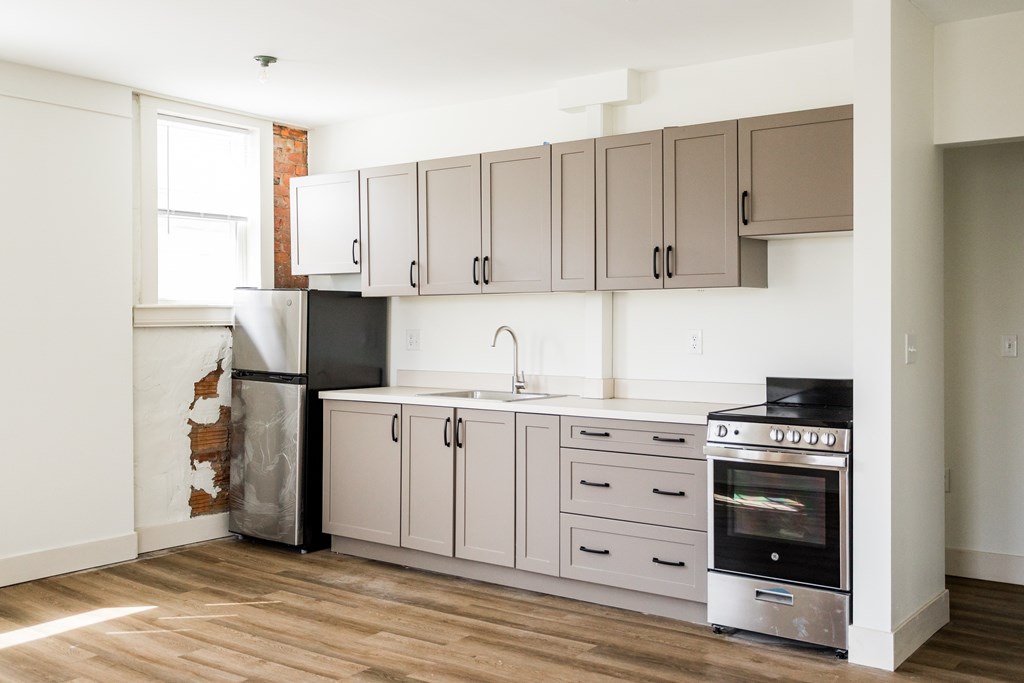 A kitchen with a refrigerator, oven, and cabinets.