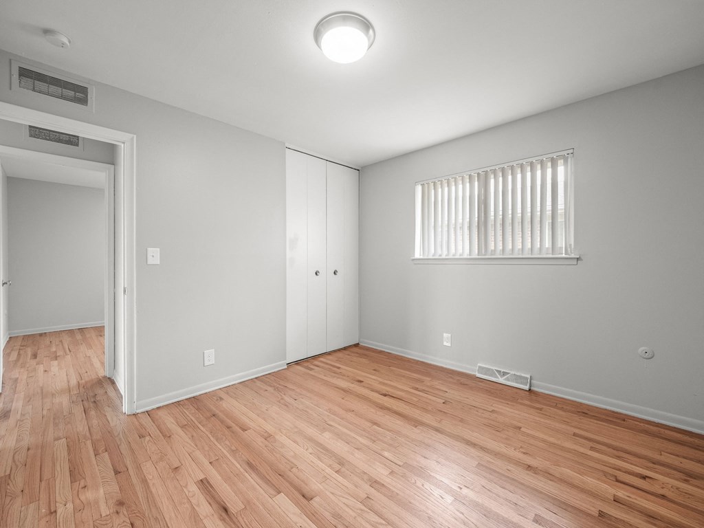 a bedroom with hardwood floors and grey walls