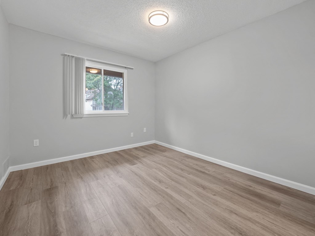 an empty living room with wood floors and a window