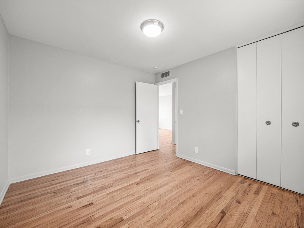 a bedroom with white walls and hardwood floors