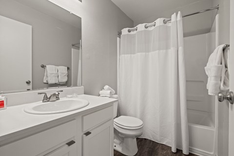 A white bathroom with a toilet, sink, and shower.