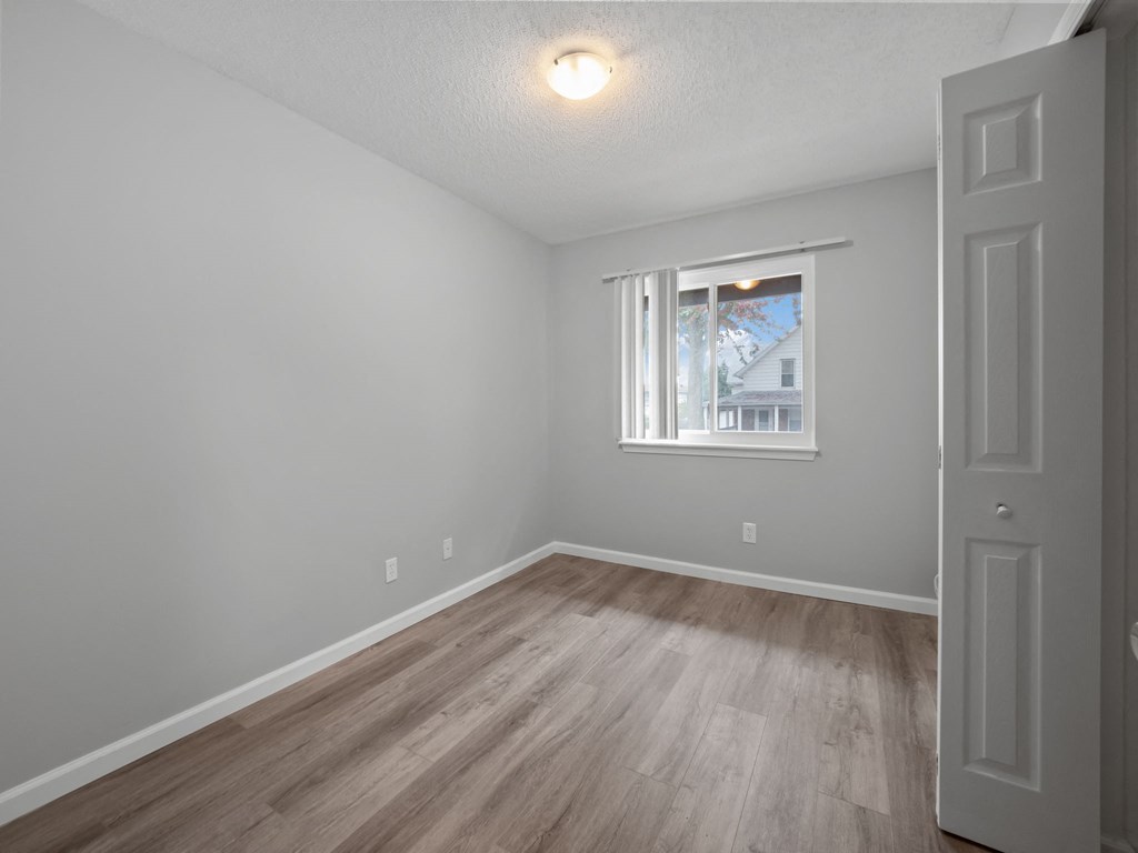 an empty room with wood floors and a window