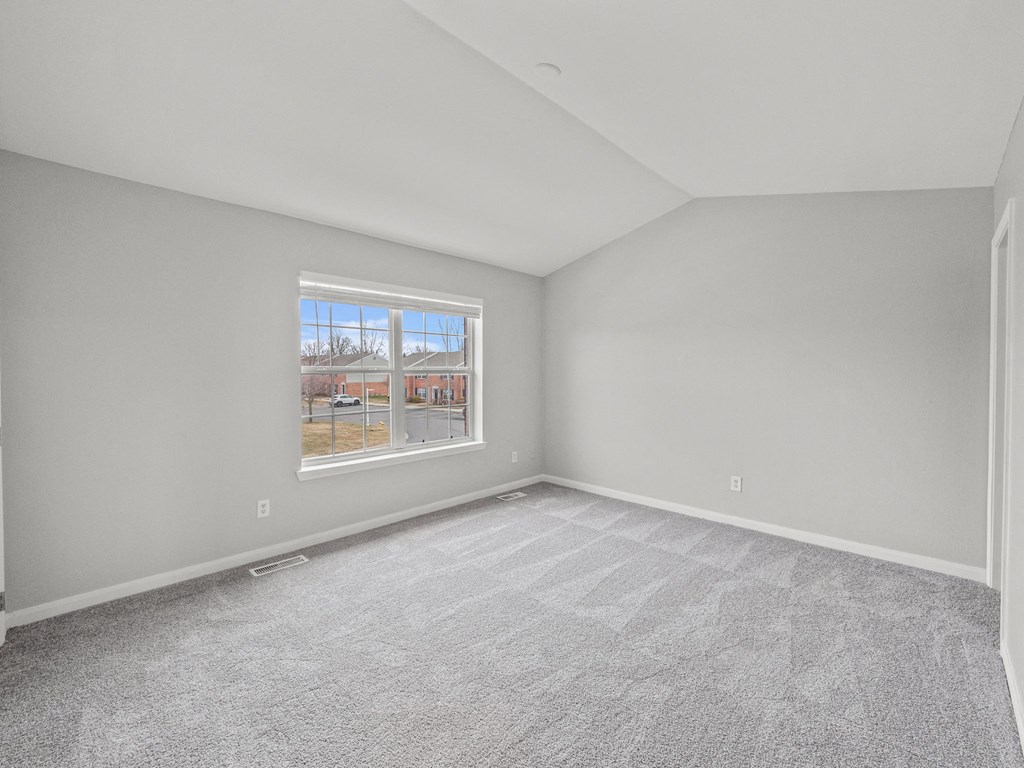 the living room of a new home with carpet and a window