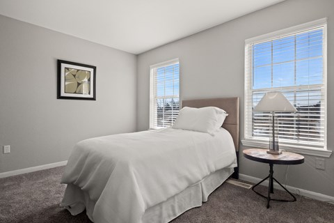 Second bedroom with a twin bed and a small table with a lamp on it.