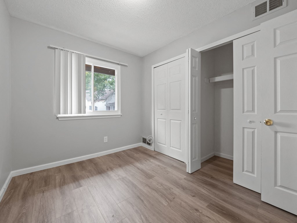 an empty bedroom with white doors and a window