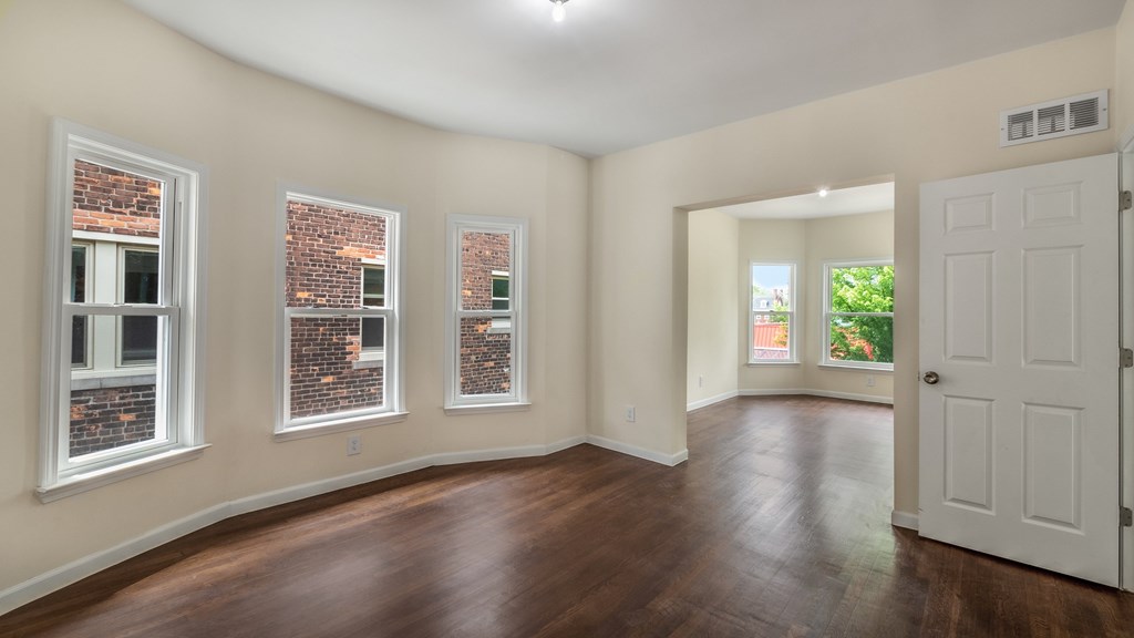 A room with a white door and three windows with brick walls.