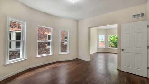 A room with a white door and three windows with brick walls.