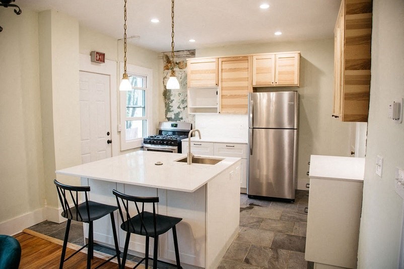 a kitchen with a white counter top and a stainless steel refrigerator