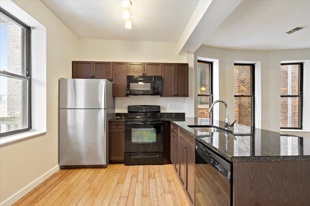 a kitchen with dark wood cabinets and a black counter top