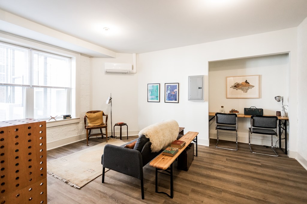 A living room with a couch, chairs, and pictures on the wall.