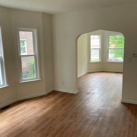 an empty room with a hard wood floor and three windows