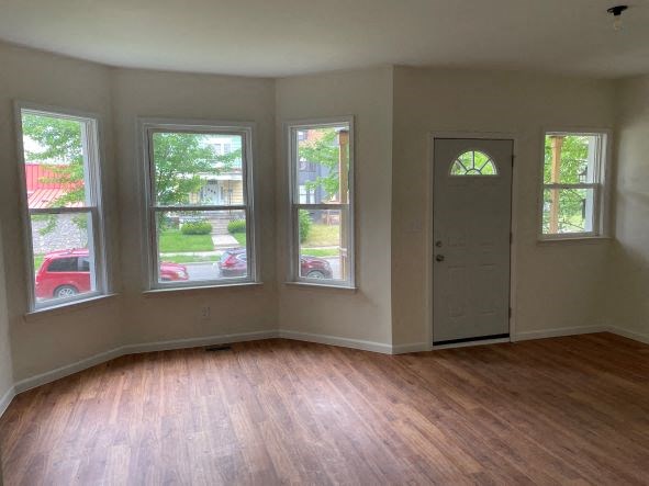 an empty living room with a door and four windows