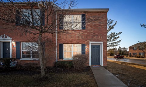 A red brick house with a grey door and windows.