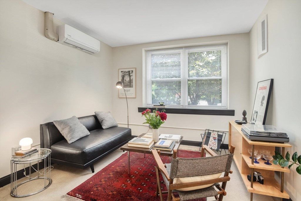 A living room with a black couch, a red rug, and a wooden chair.