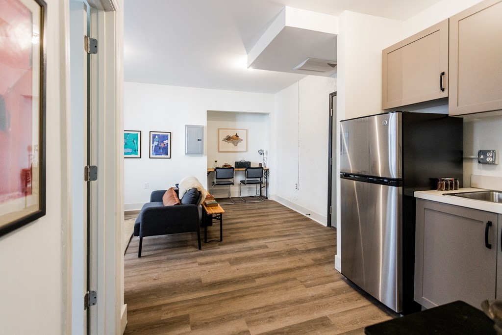 A kitchen with a refrigerator, sink, and cabinets.
