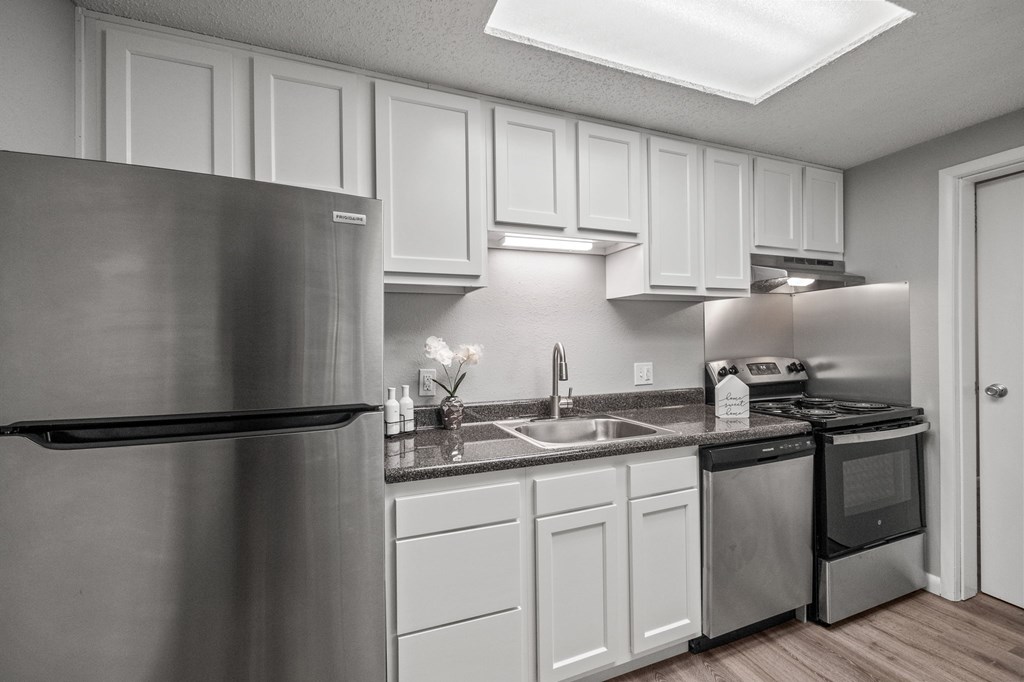A kitchen with a stainless steel refrigerator and white cabinets.