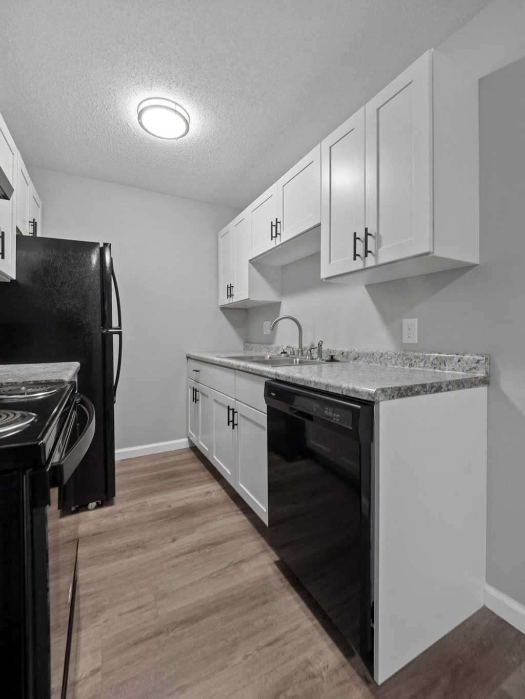 a kitchen with white cabinets and a black refrigerator