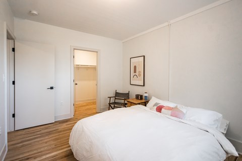 A bedroom with a large bed and a chair.