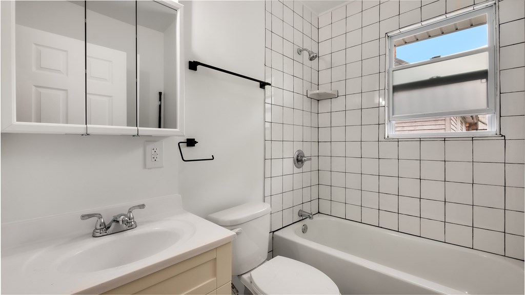 A white bathroom with a tub, sink, and toilet.