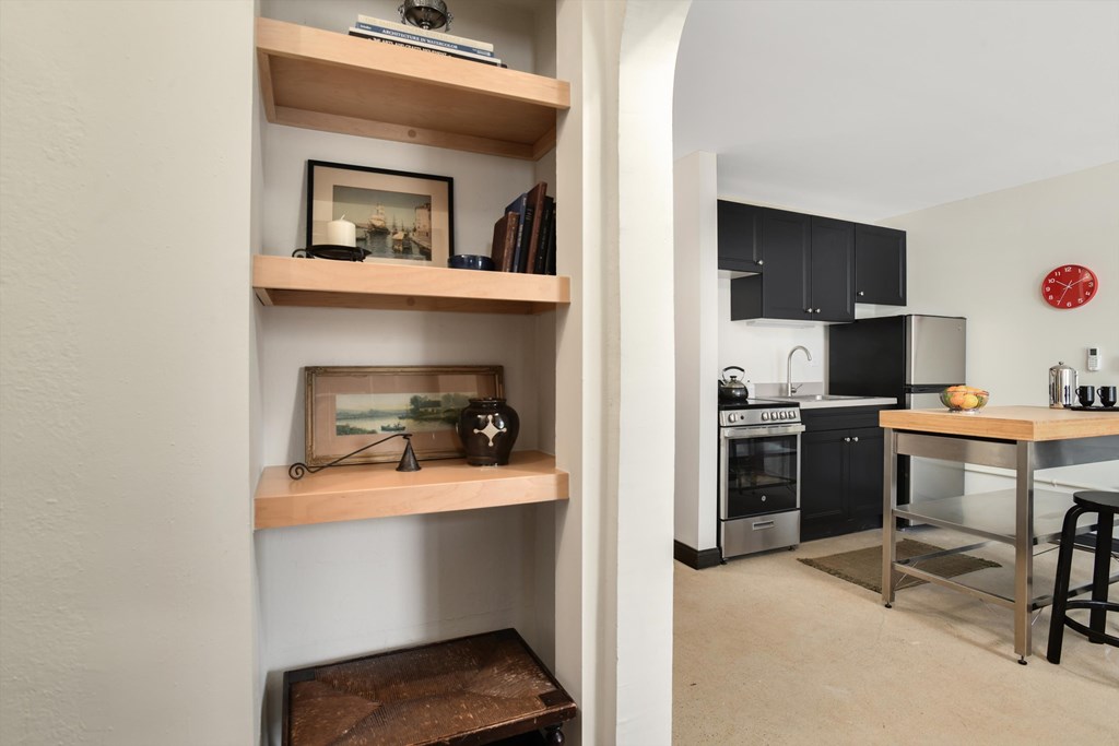 A kitchen with a table and a framed picture on the shelf.