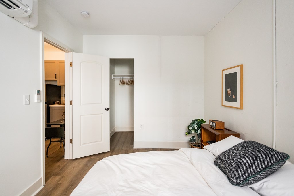 A bedroom with a white bed and a picture frame on the wall.