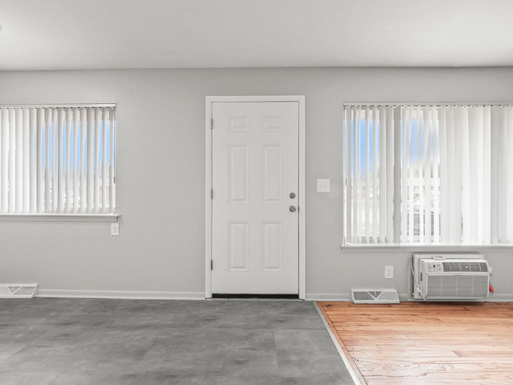 an empty room with a door and two windows