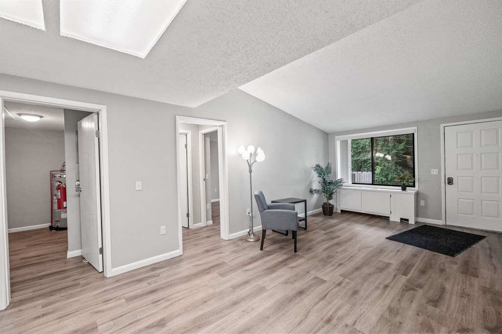A room with a wooden floor and a window with a view of trees.