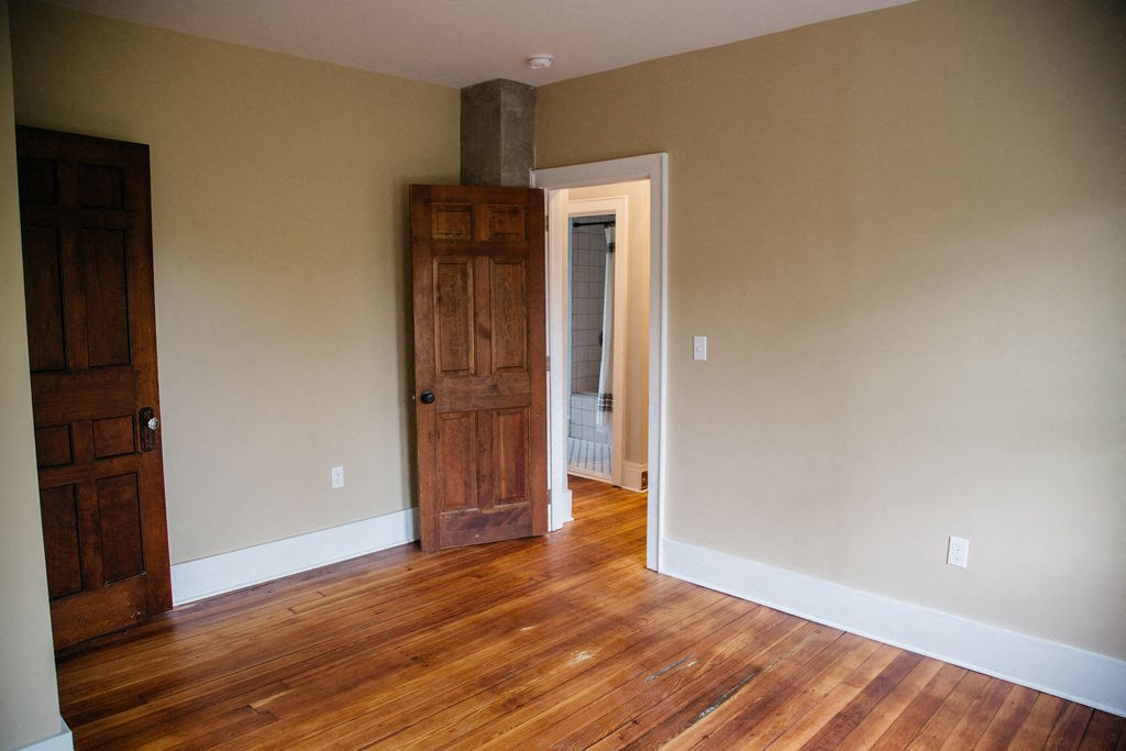 a living room with a wooden floor and a wooden door