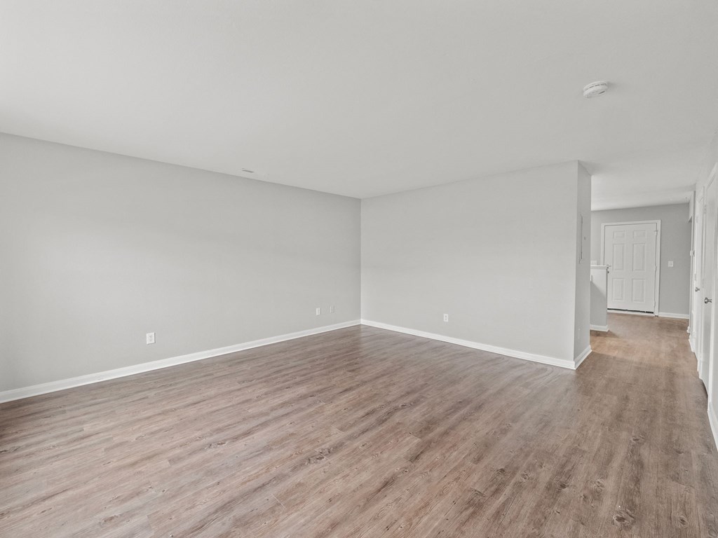 an empty living room with wood flooring and white walls