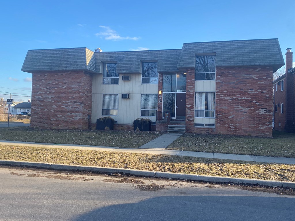 a brick house with a sidewalk in front of it